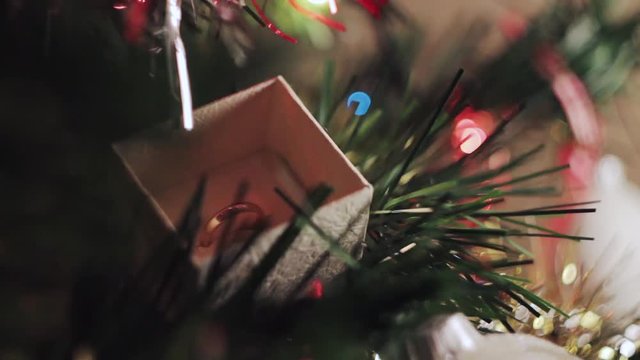 Woman opening a christmas gift and there is a wedding ring on a christmas tree