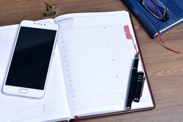 Business accessories on desktop: notebook, diary, fountain pen.