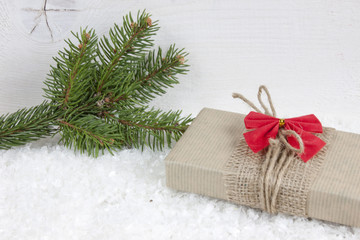 Christmas gift on snow on white wood background