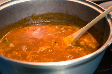 Bolognese sauce in an aluminum pot being cooked on the stove