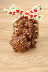 A stack of star shaped German Gingerbread with almonds decorated with a cute Christmas ribbon isolated on light brown wooden background.