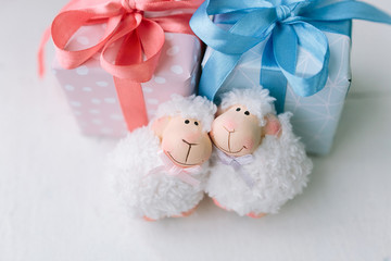 pink and blue boxes with gifts. two small toys - lambs.