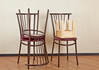 Three identical wooden chair and children's stool against the wall