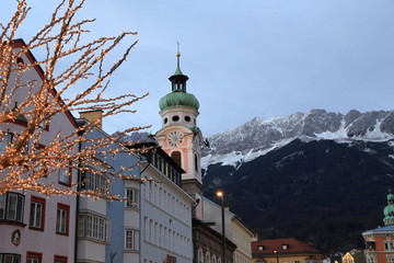 Obraz premium Roofs of Innsbruck with mountains on a background and Christmas lights on a foreground at evening 
