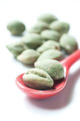 cacahuètes au wasabi et petite cuillère rouge sur fond blanc
