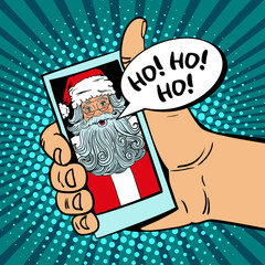 Ho! Ho! Ho! Male hand holding a smartphone with Santa Claus with open mouth on screen and speech bubble. Vector illustration in retro comic style. Pop art background. Christmas party invitation.