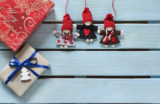 Cajas envueltas y decoradas para regalo y duendes hechos en fieltro y madera, sobre una mesa de madera azul. Imagen capturada con la suave luz de una ventana. Espacio para publicidad.
