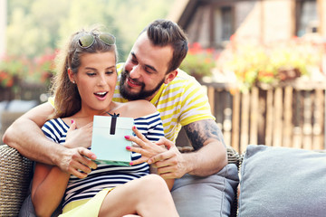 Happy couple with present sitting outside