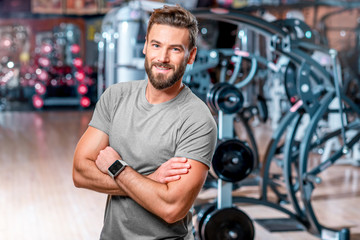 Fototapeta na wymiar Lifestyle portrait of handsome muscular man standing in the sport gym