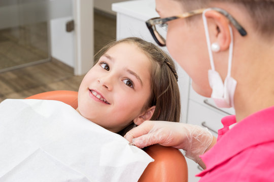 Mädchen auf dem Zahnarztstuhl lächelt entspannt zur Zahnarzthe