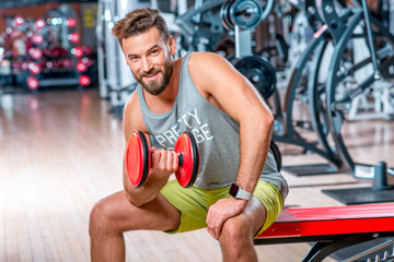 Muscular man training with red dumbbell in the gym