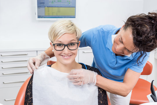 Zahnarzthelferin bereitet lächelnde Patientin für Behandlung v