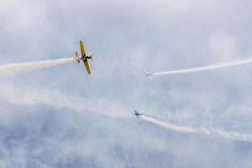 avia show. 3 small aircrafts depict acrobatics in the sky blowing smoke