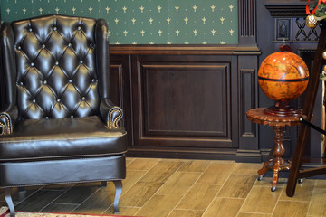 Коричневое кожаное кресло и глобус в комнате - obrazy, fototapety, plakaty