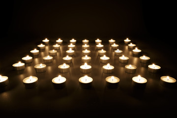 Rows of votive candles burning in the darkness