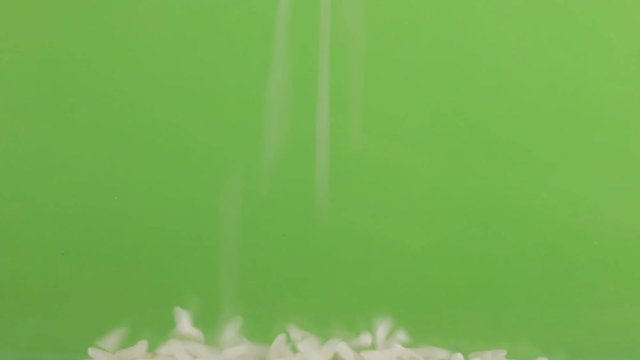Falling grains of rice on a pile of rice on a green screen.