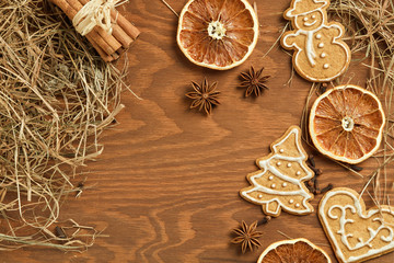Christmas gingerbread on brown, wooden background with various decoration and spices