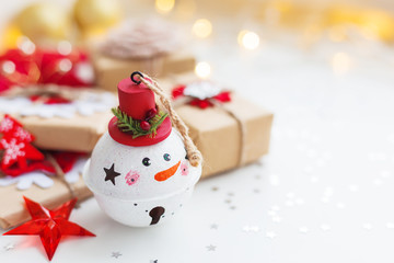 Christmas and New Year background with Snowman decorative ball, presents and decorations for Christmas tree. Holiday background with stars confetti and light bulbs. Place for text.