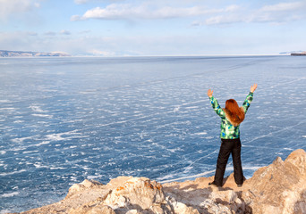 Freedom redhead woman with arms rised enjoying frozen lake