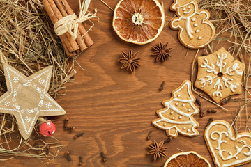Christmas gingerbread on brown, wooden background with various decoration and spices