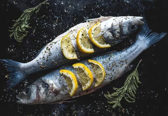 Foto auf Acrylglas Fish Wolfsbarschfisch mit Zitrone auf Tafel. Grillvorbereitung