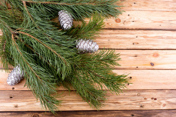 Pine branches with silver cones on wooden table