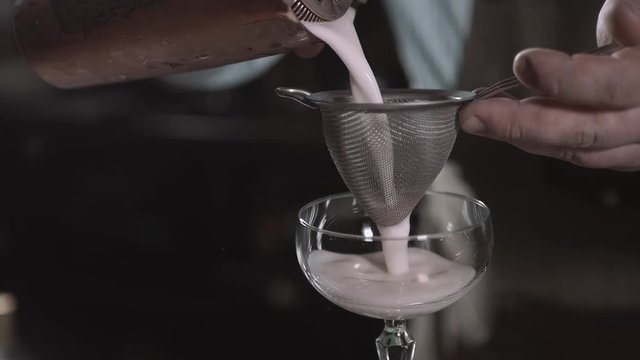 bartender preparing coctail with bar equipment, throw sieve and spray it