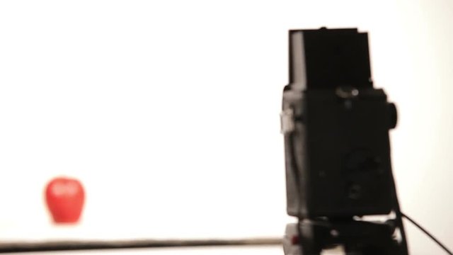 Camera refocuses from the apple on to the vintage camera during the shooting