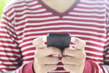 Closeup hand of woman using smartphone in the park,technology or communication concept.