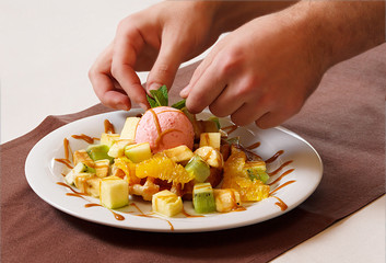 chef decorating fruit salad with ice-cream