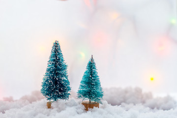 two small green toy Christmas tree on a wooden background as  symbol of the new year with place for text, next to white  balls