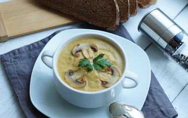 Pumpkin, carrot and Champignon mushrooms soup with cream and parsley on light green background Top view 