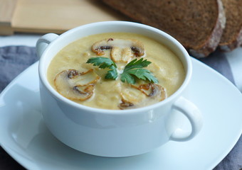 Pumpkin, carrot and Champignon mushrooms soup with cream and parsley on light green background Top view 