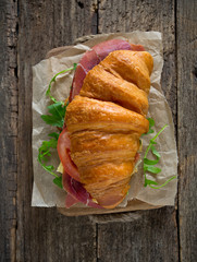 croissants with argugula, jamon, cheese and tomato on wooden sur