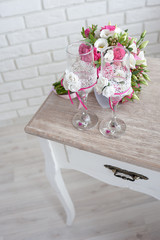 bridal bouquet with wedding rings and  wine glasses on the table in the morning of the  day