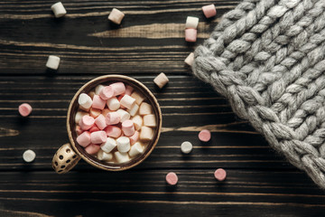 cocoa cup with colorful marshmallows and big yarn on rustic wood