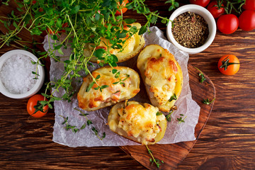 Hot Baked stuffed Potato with cheese, bacon, parsley on wooden table.
