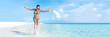 Sexy bikini body woman playful on paradise tropical beach having fun playing splashing water in freedom with open arms. Beautiful fit body girl on travel vacation. Banner crop for copyspace.