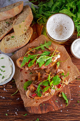 Grilled Steak Sandwich with mushrooms, goat's cheese butter and rucola leaves on top. gold beer.
