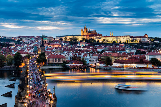 View on Prague and its famous Charles bridge over Vltava river soon after sunset with boat lights trails
