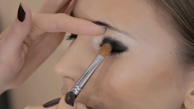 Professional makeup artist applies makeup to a beautiful model. Colors eye