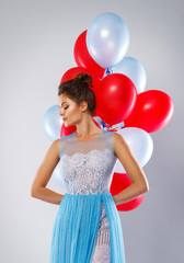 Woman wearing beautiful dress with a lot of colorful balloons