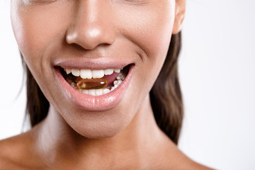 Obraz premium Happy girl is holding medicine in her mouth