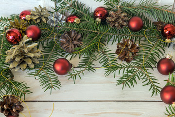 Naklejka na ściany i meble Christmas decoration with branches from fir cones and toys on white wooden background