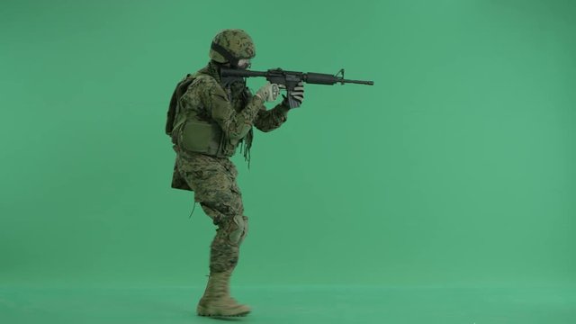 Soldier going and targeting at the camera at green screen