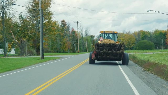 Tractor rides on the road slowly, prevents drive car. New York State, USA A typical area