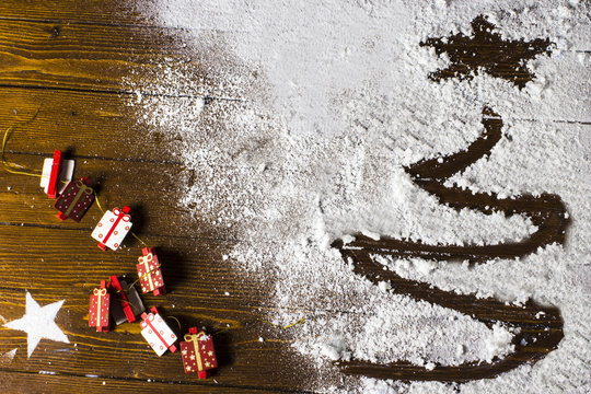 Albero di Natale disegnato nella neve, addobbi natalizi su tavolo in legno