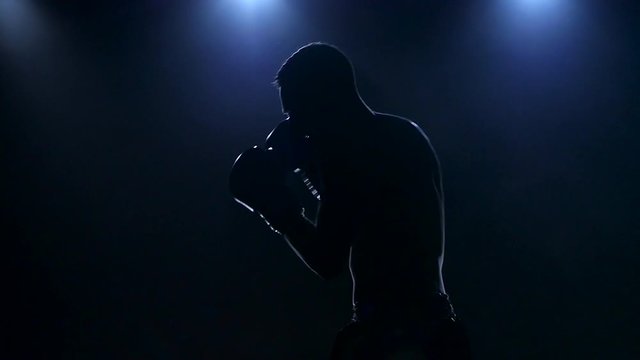 Right hook. Workout boxer in the dark studio. Slow motion