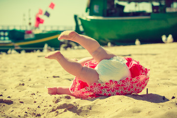 Small child fell over on the sand.