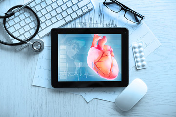 Tablet and keyboard on table. Heart on screen. Medicine and modern technology concept.